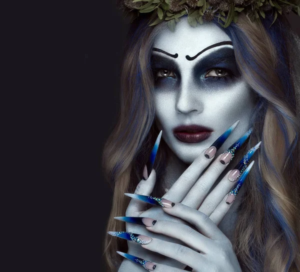 Portrait of a horrible scary Corpse Bride in wreath with dead flowers, halloween makeup and long manicure.Design of nails