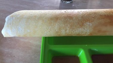 Tayland yemeği yiyen bir adamın görüntüsü. Dosa (thosai, tosai) Hint alt kıtasından gelen, mayalanmış bir hamurdan yapılan, genellikle köri, dhal ve turşuyla birlikte gelen bir krep türüdür.