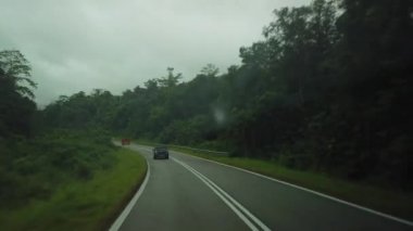 Yağmurlu bir günde, Kuching 'den Lundu' ya kadar Sarawak kırsalından geçen bir arabanın içindeki manzara.