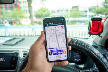 Arabanın içinde Waze navigasyon uygulaması olan iPhone X 'i tutan bir adam. Waze iyi seyrüsefer için popülerlik kazandı.