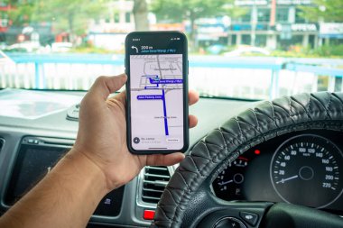Arabanın içinde Waze navigasyon uygulaması olan iPhone X 'i tutan bir adam. Waze iyi seyrüsefer için popülerlik kazandı.