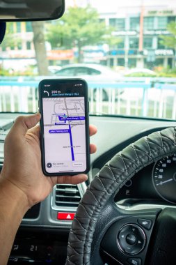 Arabanın içinde Waze navigasyon uygulaması olan iPhone X 'i tutan bir adam. Waze iyi seyrüsefer için popülerlik kazandı.