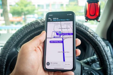 Arabanın içinde Waze navigasyon uygulaması olan iPhone X 'i tutan bir adam. Waze iyi seyrüsefer için popülerlik kazandı.