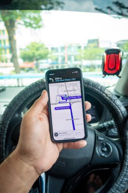 Arabanın içinde Waze navigasyon uygulaması olan iPhone X 'i tutan bir adam. Waze iyi seyrüsefer için popülerlik kazandı.