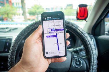 Arabanın içinde Waze navigasyon uygulaması olan iPhone X 'i tutan bir adam. Waze iyi seyrüsefer için popülerlik kazandı.