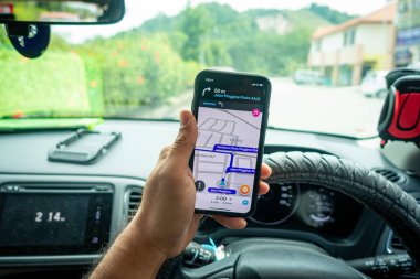 Arabanın içinde Waze navigasyon uygulaması olan iPhone X 'i tutan bir adam. Waze iyi seyrüsefer için popülerlik kazandı.