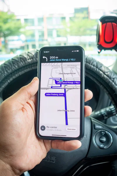 Arabanın içinde Waze navigasyon uygulaması olan iPhone X 'i tutan bir adam. Waze iyi seyrüsefer için popülerlik kazandı.