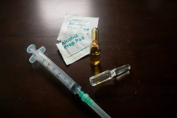 Medication ampoules for Intravenous injections on a wooden background with empty syringe and alcohol swab, medical concept