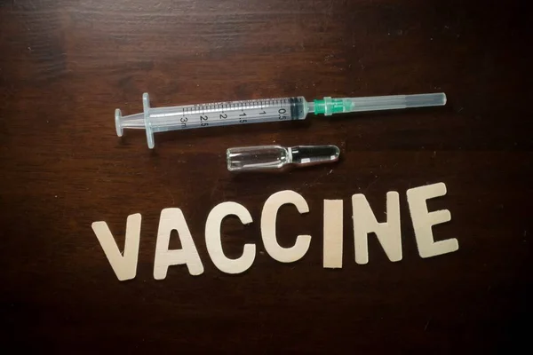 Vaccine wordings with empty syringe and vaccine ampoules on a wooden table, Vaccination concept, medical