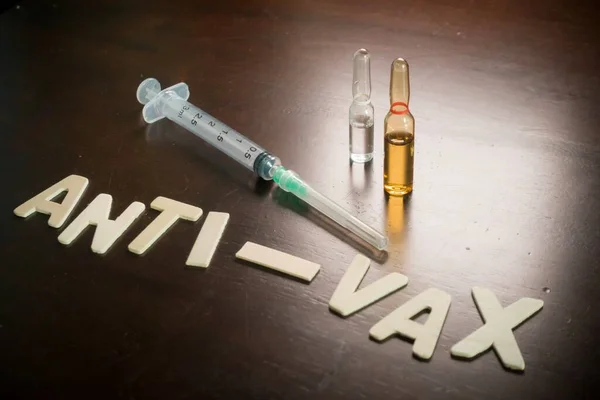 Boş şırınga ve aşı ampulleri olan Vax karşıtı sözcükler ahşap bir masa, aşı konsepti, tıbbi