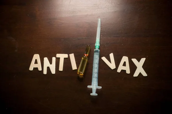 Boş şırınga ve aşı ampulleri olan Vax karşıtı sözcükler ahşap bir masa, aşı konsepti, tıbbi