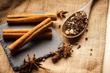 Bir paçavranın tepesindeki tahta kaşıkta çeşitli baharatlar.