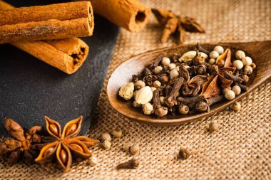 Bir paçavranın tepesindeki tahta kaşıkta çeşitli baharatlar.