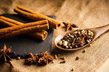 Bir paçavranın tepesindeki tahta kaşıkta çeşitli baharatlar.