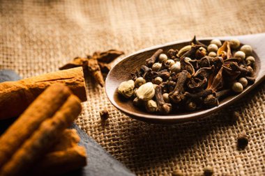 Bir paçavranın tepesindeki tahta kaşıkta çeşitli baharatlar.