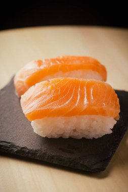 Somon nigiri sushi, siyah bir tabakta servis edilir, seçici bir odak noktası vardır.