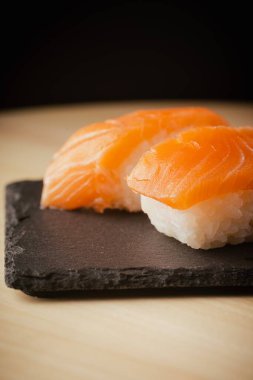 Somon nigiri sushi, siyah bir tabakta servis edilir, seçici bir odak noktası vardır.