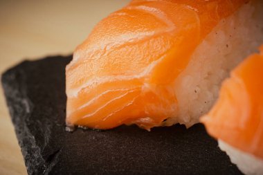 Somon nigiri sushi, siyah bir tabakta servis edilir, seçici bir odak noktası vardır.