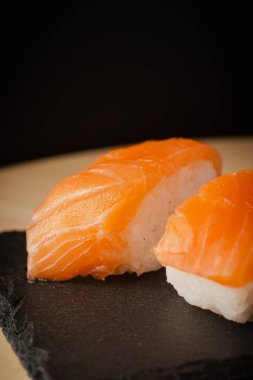 Somon nigiri sushi, siyah bir tabakta servis edilir, seçici bir odak noktası vardır.
