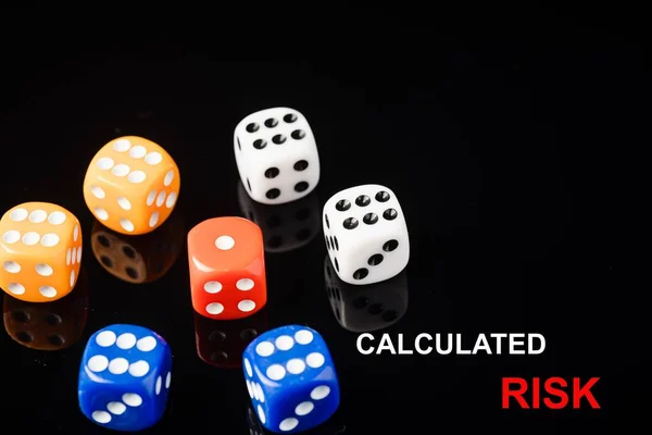 CALCULATED RISK wordings with red dices surrounded by blue, orange and white diceS