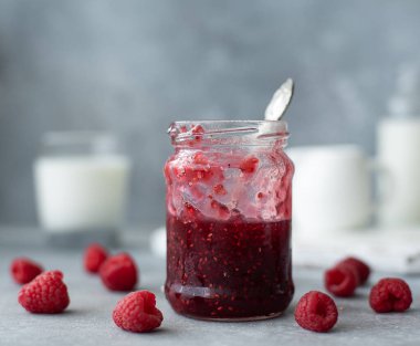 Cam kavanozda ahududu reçeli ve kaşık.