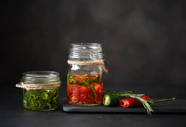 Röd och grön chili paprika i en glasburk med olivolja — Stockfoto