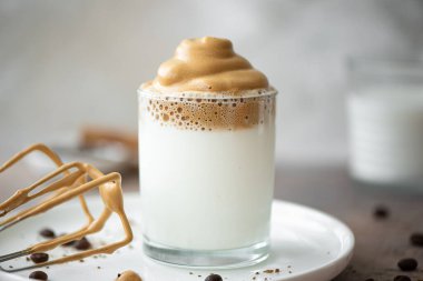 Dalgona kahvesi, beyaz tabakta bardakta kahve çekirdekleri.