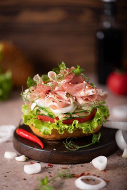 Pastırmalı sandviç, marul, soğan, salatalık ve domatesli susamlı çörek.