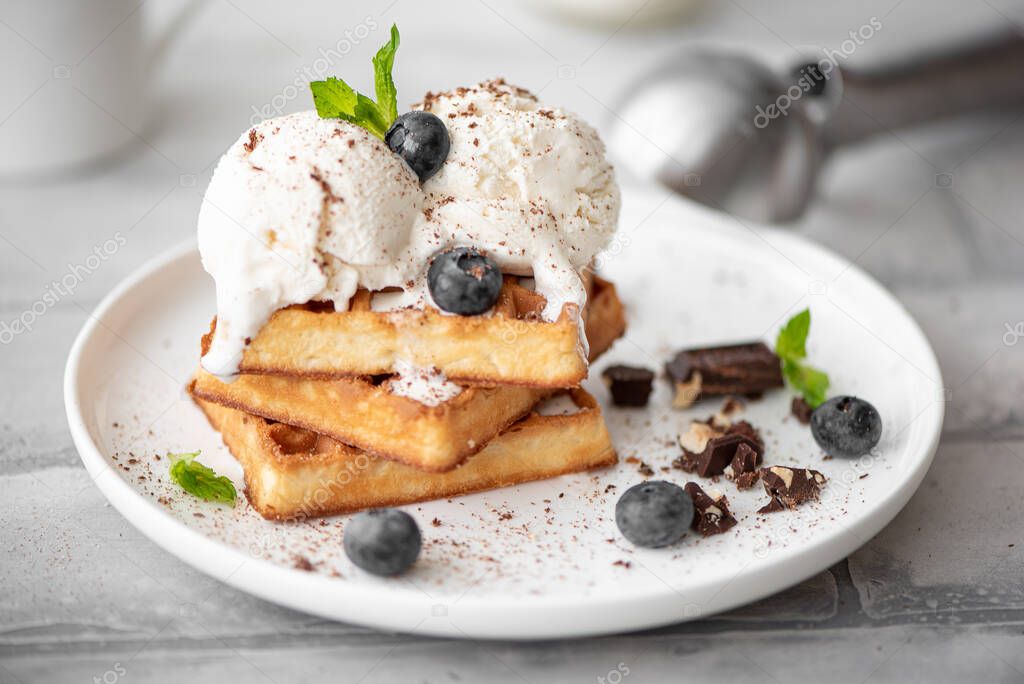 homemade waffles with two scoops of ice cream and chocolate on white plate
