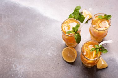 Limonlu buzlu çay, büyük bardakta zencefil ve nane, gri arka planda, tpo manzaralı.