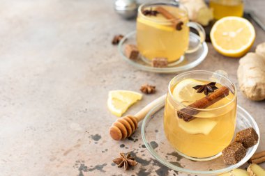 Sıcak bitkisel çay, limon, zencefil, tarçın ve bal, cam bardaklarda.