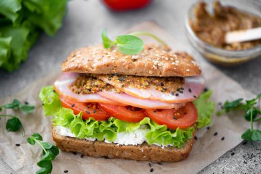 Jambonlu sandviç, marul, domates ve hardallı parşömen.