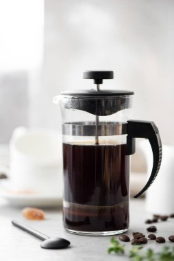 Küçük beyaz bardaklı, cam bir kahve demliğinde sade sıcak kahve.