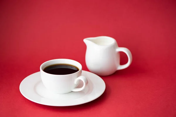 กาแฟด าในถ วยกาแฟขนาดเล กและเหย อกนมบนพ นหล แดง — ภาพถ่ายสต็อก