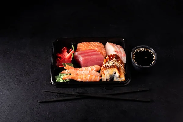 Sashimi Uppsättning Lax Räkor Tonfisk Och Svart Plastbehållare Mörk Bakgrund — Stockfoto