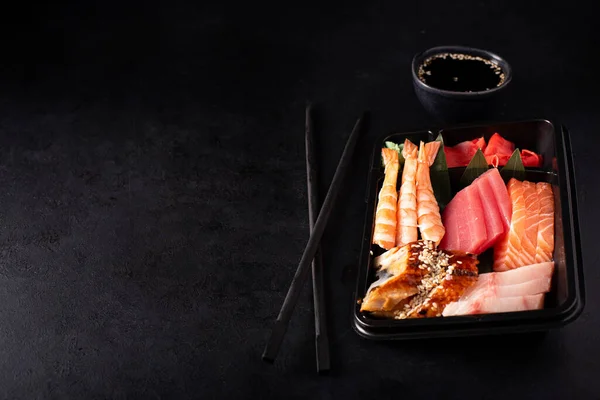 Sashimi Uppsättning Lax Räkor Tonfisk Och Svart Plastbehållare Mörk Bakgrund — Stockfoto