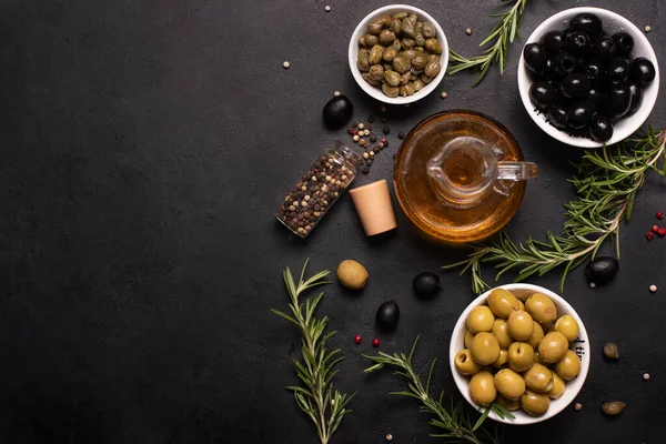 olive oil in a glass bottle with olives, herbs and spices