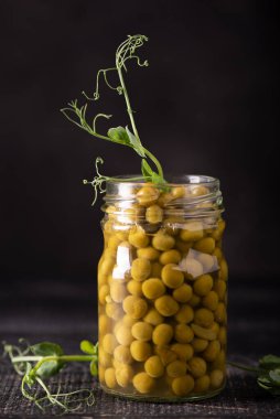 Cam kavanozdaki konserve yeşil bezelyeler.