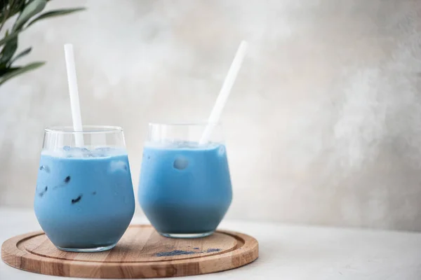 iced blue matcha tea with milk in glass on a wooden board