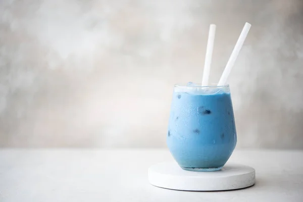 iced blue matcha tea with milk in glass on a wooden board