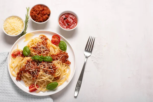 spaghetti with meat sauce, parmesan and basil on a white plate