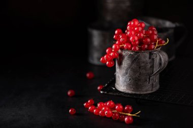 Siyah bir zemin üzerinde demir bir fincanda üzümlü kırmızı bir demet.