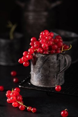 Siyah bir zemin üzerinde demir bir fincanda üzümlü kırmızı bir demet.