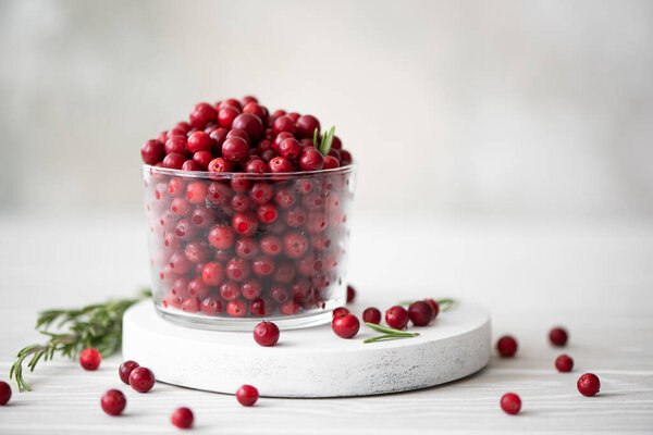 ripe lingonberries in a glass bowl on a white board