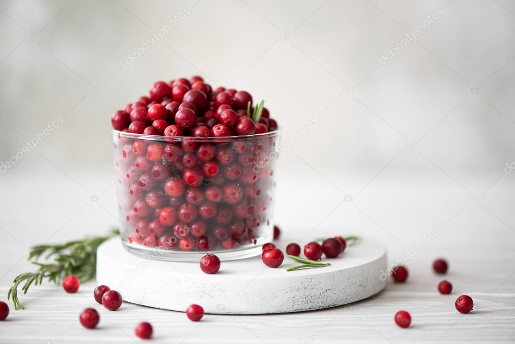 ripe lingonberries in a glass bowl on a white board