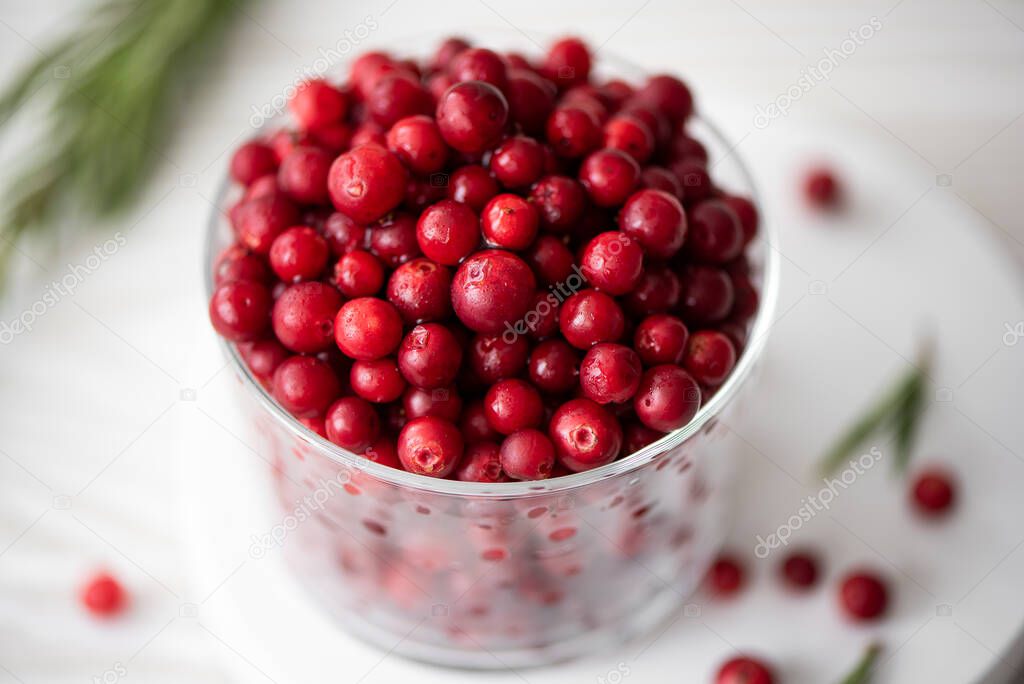 ripe lingonberries in a glass bowl on a white board