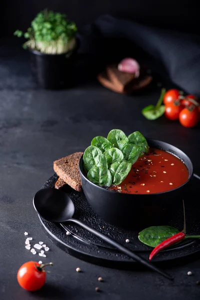 tomato puree soup with spinach in a black bowl