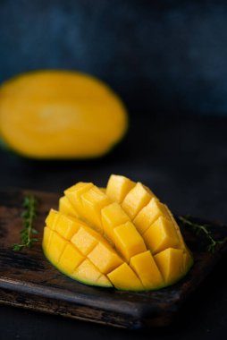 Büyük, olgun bir mango koyu mavi bir arkaplanda parçalara ayrılmış.