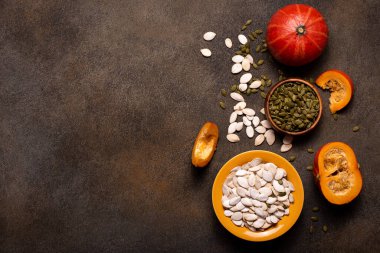 Küçük portakal kabakları ve kabak çekirdekleri koyu bir masada, üst tarafta.