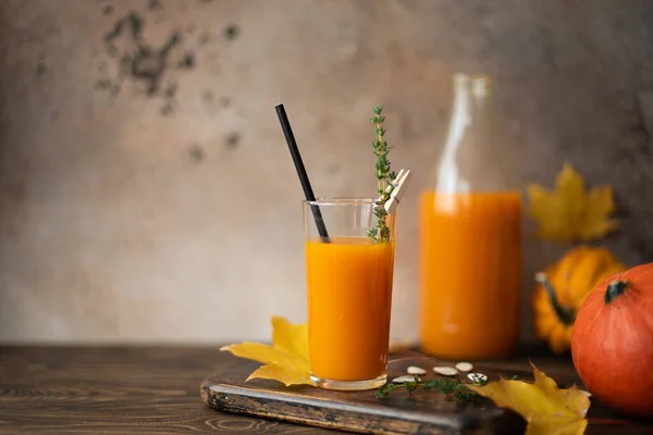 pumpkin juice in a bottle and glass on a wooden table